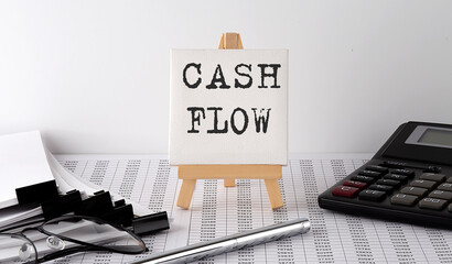 text CASH FLOW on easel with office tools and paper.Top view. Business concept