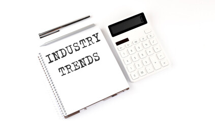 Notepad with text INDUSTRY TRENDS with calculator and pen. White background. Business