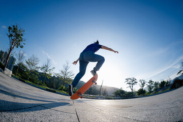 Asian woman skateboarder skateboarding in sunrise city