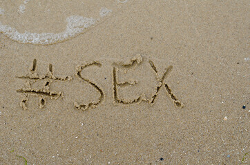 Fototapeta na wymiar Hashtag and the word SEX written in the wet sand. Handwritten wo