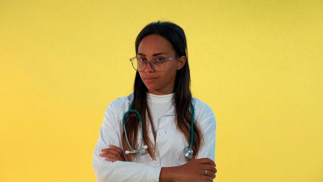 Serious Black Female Doctor Saying No To Somebody. There Is Yellow Background.