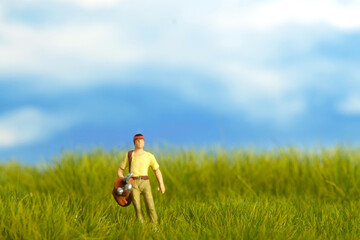 Miniature people toy figure photography. A men caddy golf putter standing at meadow golf field on...