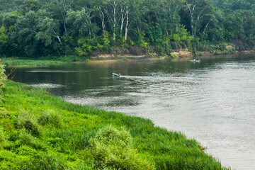 Fishing boats on the river among the green banks
