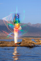 Yoga meditation outdoors. Glowing seven all chakra. Woman sits in a Upward Salute Lotus pose on...