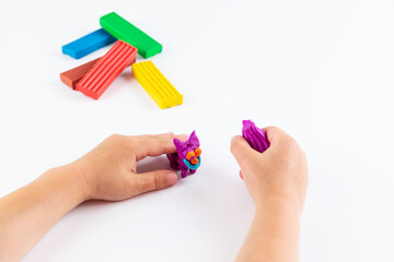 A figure from modelling clay in the hands of a child on a white background.