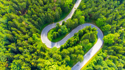 Asphalt road serpentine in the forest. Aerial view from drone. - obrazy, fototapety, plakaty