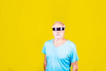 Elderly caucasian man wearing smart sci-fi glasses on yellow background with advertising copyspace