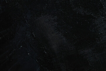 Dark creative background - rough linen canvas unevenly covered with black primer, reflections of light. Toning, blurring, selective focus.