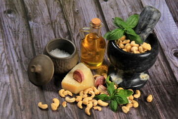 Pesto Ingredients: Fresh Basil, Garlic, Cashew Nuts, Olive Oil and Cheese, copy space, Ingredients for making pesto sauce on a dark wooden background, top view. pesto with Cashew 