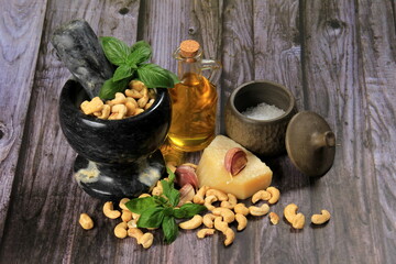 Pesto Ingredients: Fresh Basil, Garlic, Cashew Nuts, Olive Oil and Cheese, copy space, Ingredients for making pesto sauce on a dark wooden background, top view. pesto with Cashew 