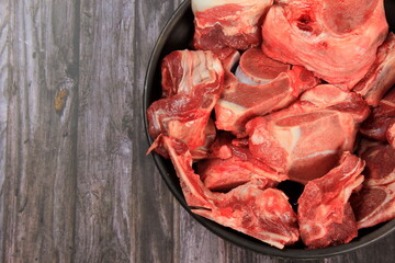 Raw beef bones in round clay bowl on wooden table. Beef selection for soup, Copy space 