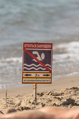 Ban on swimming in the sea. Warning sign. Information plate. Dangerous zone. Swimming is prohibited. Safety on the water. Signpost on the beach. Coastal zone.