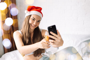 Girl in bed makes selfie with glass of champagne