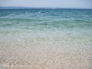 Scenic shining view of the clear water of Adriatic Sea on a sunny summer day. Colorful natural fresh background for creative illustration with shiny blur effect. Bright nautical scape beauty closeup