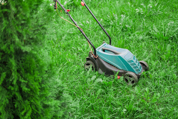 A lawn mower on lush green grass in a modern garden.