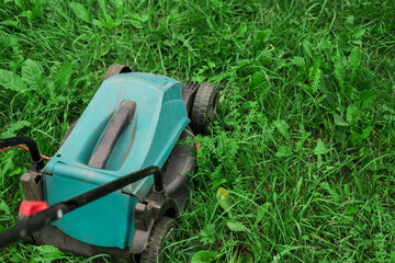 Fototapeta premium A lawn mower on lush green grass in a modern garden.