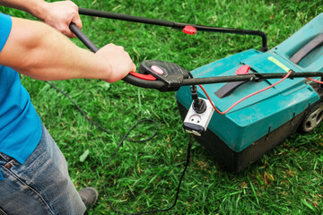 The gardener mows the lawn. Lawn mower on lush green grass in a modern garden.