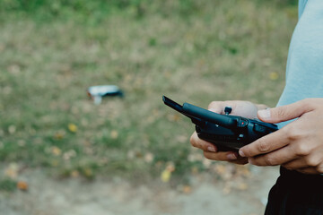 Female hands with controls a quadcopter drone outdoors in autumn. The woman begin start to the drone. Woman controling flying drone in the park