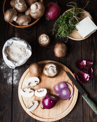 Prepare a pie with champignons, red onions and feta cheese. Products for cooking on a brown table. Flour, butter, onion, mushrooms, thyme. Mushroom biscuit. Greek cuisine.