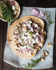 Prepare a pie with champignons, red onions and feta cheese.The cooking process on a brown table. Dough, onion, mushrooms, thyme. Mushroom biscuit. Greek cuisine.