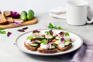 Canapes with toasted bread with sunflower and flax seeds, feta cheese, cucumber and onion