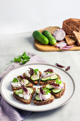 Canapes with toasted bread with sunflower and flax seeds, feta cheese, cucumber and onion