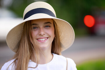 portrait of a 12-year-old girl in a hat on the background of the road