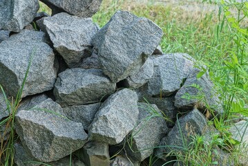 pile of gray stones on the street in green grass and vegetation