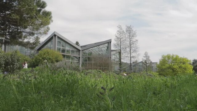A vitreous, glassy building and walking tourists in the Palm Garden, Frankfurt, Germany