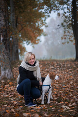 Fototapeta premium Young woman with happy beagle dog walking and playing in autumn leaves