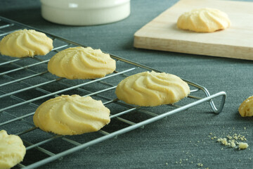 Close up image homemade butter cookies put on wire rack and a mug with wooden tray on the table.