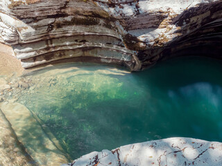 A bright turquoise calm river flows between the canyons. A pond in the middle of the rocks
