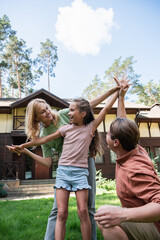 Positive family holding hands on meadow outdoors