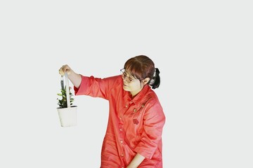 붉은색 옷을 입은 한국의 평범한  50대 주부가 작은 꽃이 핀 꽃 바구니를 들고 있는 모습입니다.  - obrazy, fototapety, plakaty