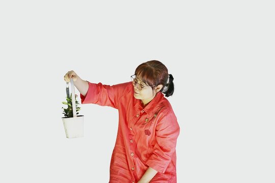 붉은색 옷을 입은 한국의 평범한  50대 주부가 작은 꽃이 핀 꽃 바구니를 들고 있는 모습입니다. 
