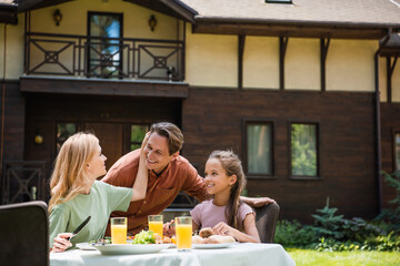 Smiling woman touching husband near daughter during picnic outdoors