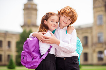 Photo of two people schoolchildren enjoy cuddle embrace show feelings wear white shirt uniform park outdoors
