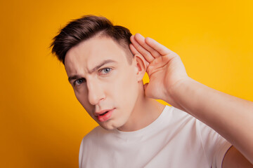 Portrait of curious guy look camera hand ear eavesdropping on yellow background