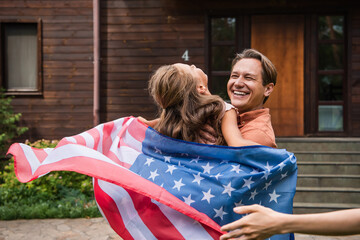 Happy father holding child with american flag outdoors