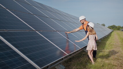 A father working in a solar power plant tells his daughter about his work, shows green energy, solar panels. Shooting at a solar power plant. Preservation of our planet, global warming