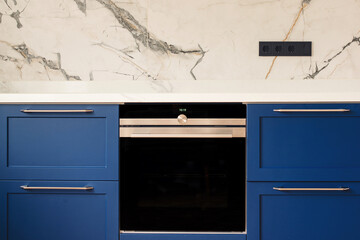 Luxury blue kitchen with marble tiled backsplash. Modern oven in stylish new kitchen.