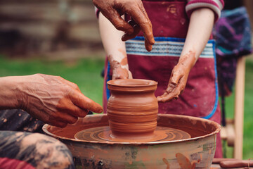 Father and son making ceramic pot. Family working on pottery wheel. Potters and child hands.
