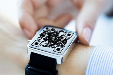 Fototapeta premium technology and health care concept - close up of woman's hands with qr code on smart watch at office