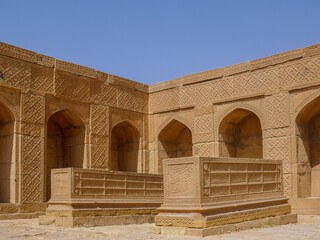 Obraz premium Beautiful carved golden sandstone cenotaphs inside courtyard of a royal mausoleum in UNESCO listed Makli necropolis, Thatta, Sindh, Pakistan