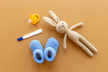 Pregnancy test with blue baby boy booties and toy, top view