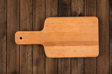 Top view on light brown wooden cutting board on a wooden background