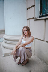 Fototapeta premium a beautiful girl in a skirt and top walks near the theater