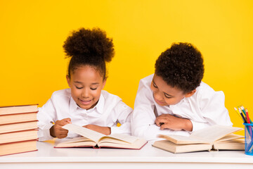 Photo of young happy afro american girl and boy desk uniform read book isolated on yellow color...