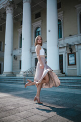 a beautiful young girl is walking around the city, spinning, dancing on the street