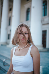 a beautiful girl in a skirt and top walks near the theater, looks into the frame, portrait, city girl